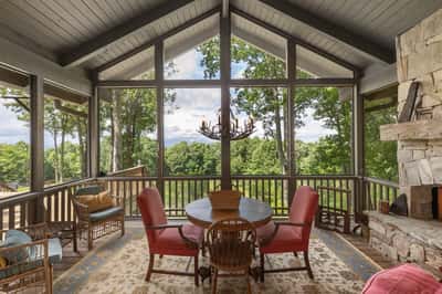 Bright, airy sunroom with panoramic views, featuring high ceilings, inviting seating, and a cozy fireplace.