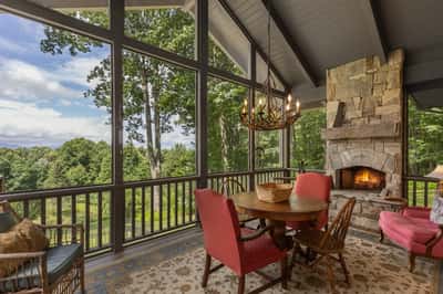 Bright and airy sunroom featuring a stone fireplace, perfect for cozy gatherings amidst nature views.