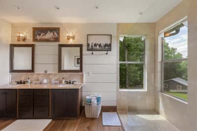 Bright and spacious bathroom featuring dual sinks, large windows, and modern fixtures for a refreshing experience.