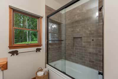 Bright bathroom featuring a modern glass shower, natural light, and rustic wood accents for a cozy atmosphere.