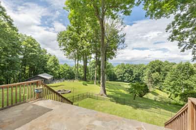 Spacious outdoor retreat featuring lush greenery, scenic views, and convenient access to a rustic outbuilding.