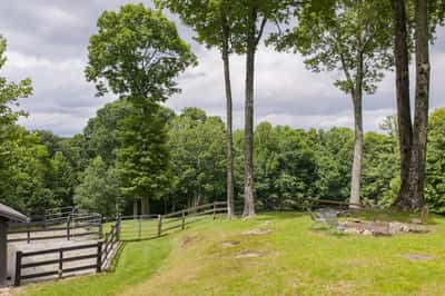 Spacious outdoor area featuring mature trees, a fenced pasture, and scenic views perfect for country living.