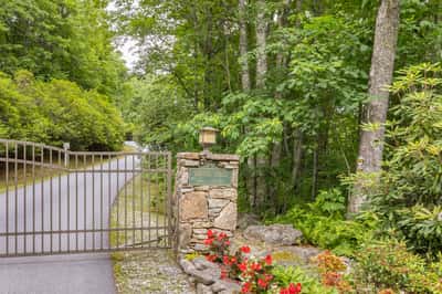Discover a private, gated entrance leading to a secluded retreat surrounded by lush greenery and vibrant flowers.