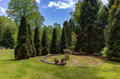 This expansive outdoor space features lush greenery and a unique stone birdbath, perfect for relaxation.