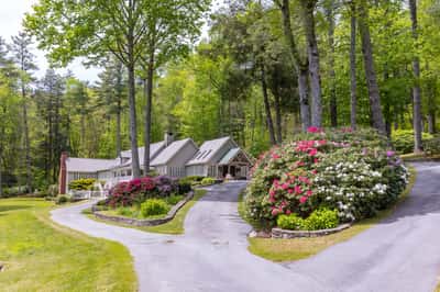 Nestled among lush greenery, this stunning property features expansive gardens and a winding driveway for added privacy.