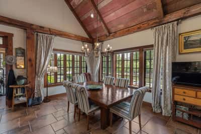 Inviting dining area featuring large windows, rustic beams, and ample space for gatherings or entertaining.