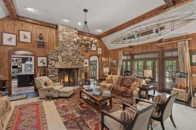 This cozy living room features a stunning stone fireplace, high ceilings, and abundant natural light.