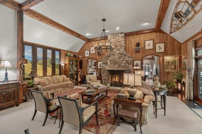 Spacious living area featuring a stunning stone fireplace and large windows with picturesque mountain views.