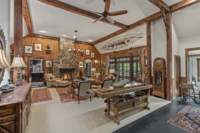 Discover a spacious living area featuring a striking stone fireplace and exposed wood beams, perfect for gatherings.