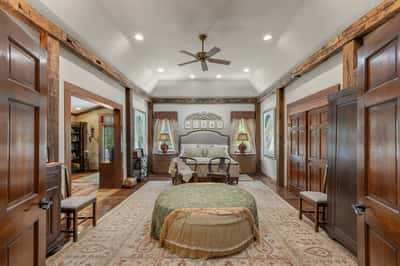 Spacious bedroom featuring rustic beams, large windows, and inviting seating, perfect for relaxation and comfort.