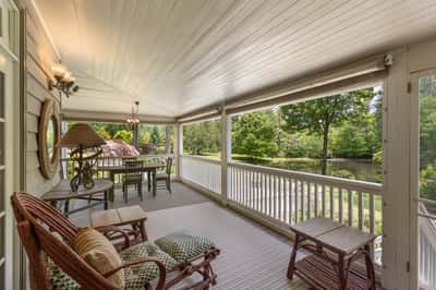 Discover this inviting covered porch, perfect for relaxing while enjoying views of the lush landscape and pond.