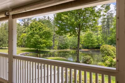 Beautiful views of a tranquil pond and vibrant greenery from the inviting covered porch.