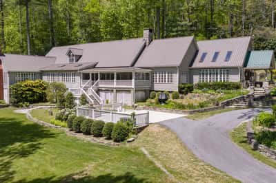 Spacious home surrounded by lush greenery, featuring ample outdoor space and unique architectural design.