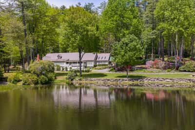 Idyllic waterfront property surrounded by lush greenery, featuring spacious interiors and picturesque landscaping throughout.