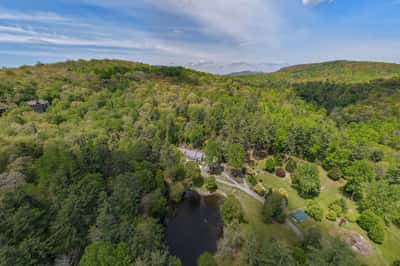 Nestled among lush greenery, this expansive property features a tranquil pond and scenic mountain views.