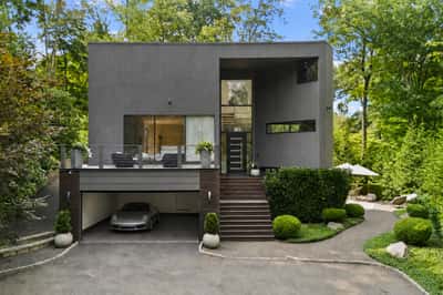 Contemporary home set among lush greenery, featuring a spacious garage and inviting outdoor living area.