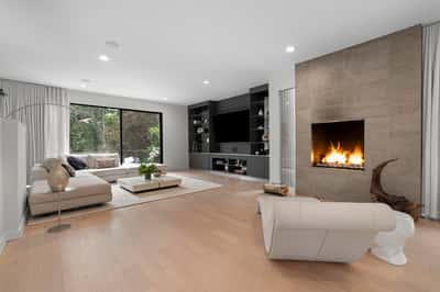Bright and spacious living area featuring a sleek fireplace and large windows that invite nature indoors.