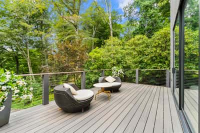 Spacious outdoor deck surrounded by lush greenery, perfect for relaxation and entertaining in nature.