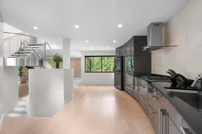 Spacious kitchen featuring modern appliances and large windows that frame picturesque greenery outside.