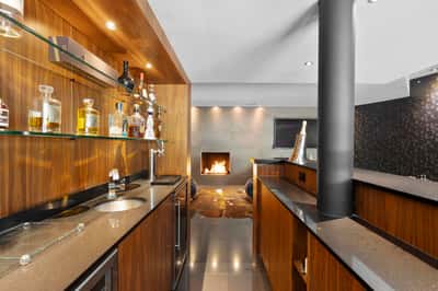 This contemporary kitchen features sleek wooden cabinetry, a cozy fireplace, and a modern ambiance perfect for entertaining.