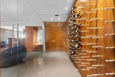 This modern entryway features a stunning wine display wall and sleek glass accents for a contemporary feel.