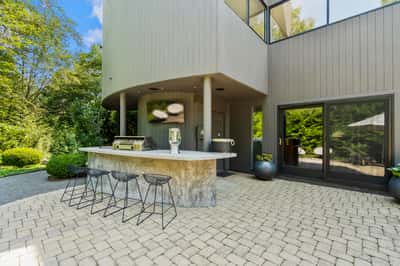 This outdoor space features a sleek kitchen island perfect for entertaining in a lush, private setting.