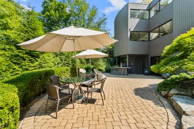 Discover a secluded outdoor space with a patio, perfect for relaxation and entertaining amidst lush greenery.