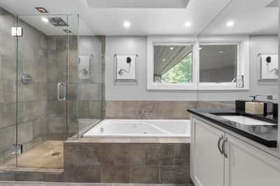 This modern bathroom features a glass-enclosed shower, soaking tub, and abundant natural light.