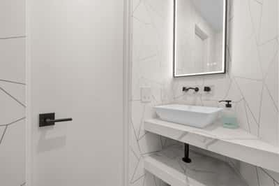 Modern bathroom featuring geometric tile accents, minimalist fixtures, and a sleek, illuminated mirror.