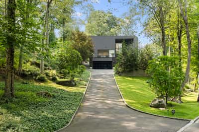 Modern home nestled within lush greenery, featuring a spacious driveway and tranquility just minutes from the city.