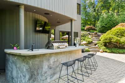Modern outdoor bar area with a sleek countertop, perfect for entertaining amid lush landscaping.