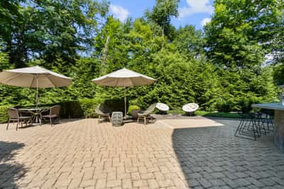 Discover an inviting outdoor space featuring ample seating, shade umbrellas, and a lush green backdrop.