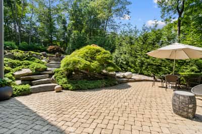 Discover a tranquil garden oasis featuring stone pathways, lush greenery, and an inviting outdoor seating area.
