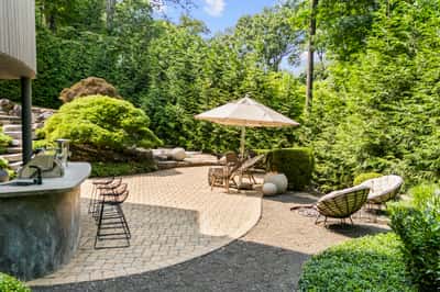Discover your private outdoor oasis, featuring tiered landscaping, lounge areas, and a shaded retreat.