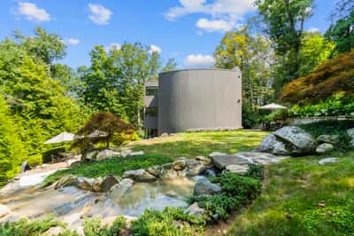 Nestled in nature, this unique home features a landscaped yard and striking architecture surrounded by lush greenery.