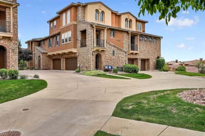 Spacious modern duplex featuring a stone exterior, ample parking, and beautifully landscaped grounds in a prime location.