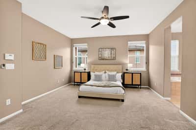 Spacious bedroom featuring abundant natural light, modern ceiling fan, and plush carpeting for comfort.