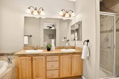 Modern bathroom featuring dual sinks, spacious counter, and a glass-enclosed shower for convenient living.