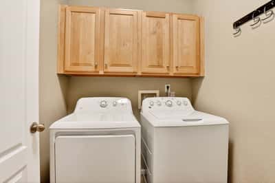 Bright laundry room featuring ample storage and modern appliances, designed for efficiency and convenience.