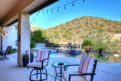 Spacious covered patio with seating and lighting overlooks the pool and mountains, ideal for Scottsdale indoor-outdoor lifestyle.