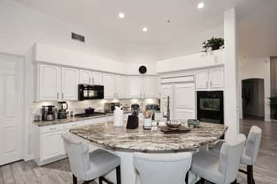 Open-concept kitchen with large island, granite counters, and white cabinetry delivers modern Scottsdale style and functionality.