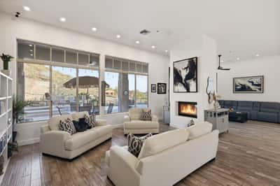 Light-filled living room with large windows, fireplace, and patio views showcases Scottsdale indoor-outdoor lifestyle and modern design.