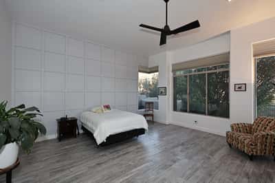 Spacious primary bedroom with high ceilings, large windows, and updated flooring offers comfort and Scottsdale luxury living.