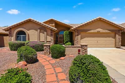 Beautifully landscaped front exterior with stone detailing, mature shrubs, and welcoming pathways enhances the curb appeal of this move-in ready Peoria residence.
