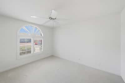 Bright secondary bedroom with plantation shutters and neutral tones offers comfortable guest accommodations or flexible office and hobby space.
