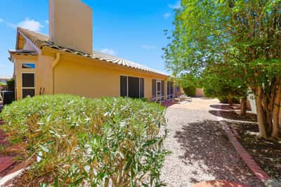Spacious backyard with mature greenery, gravel landscaping, and inviting patio seating areas offers comfortable outdoor living and entertaining opportunities.