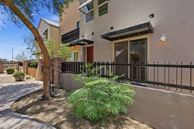 Attractive townhouse exterior featuring a private fenced patio, mature landscaping, and inviting architectural details. This Mesa home combines low-maintenance living with welcoming curb appeal.