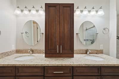 Primary bath featuring dual vanities, granite surfaces, abundant storage, and updated fixtures. The spacious layout provides convenience and a luxurious daily experience.