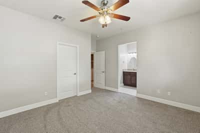 Large primary suite offering fresh carpeting, neutral colors, ceiling fan, and easy access to the ensuite bath and walk-in closet. A comfortable space to begin and end each day.