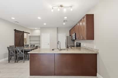 Large breakfast bar overlooking the living and dining areas creates the perfect gathering spot. Granite countertops and open-concept design add both beauty and functionality.